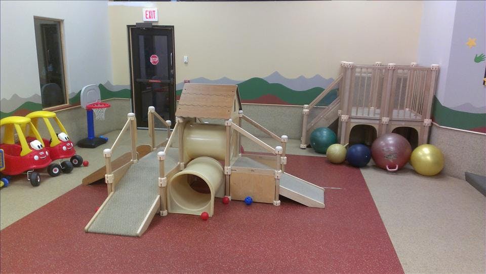 Indoor playground with slides, tunnels, small cars, and exercise balls
