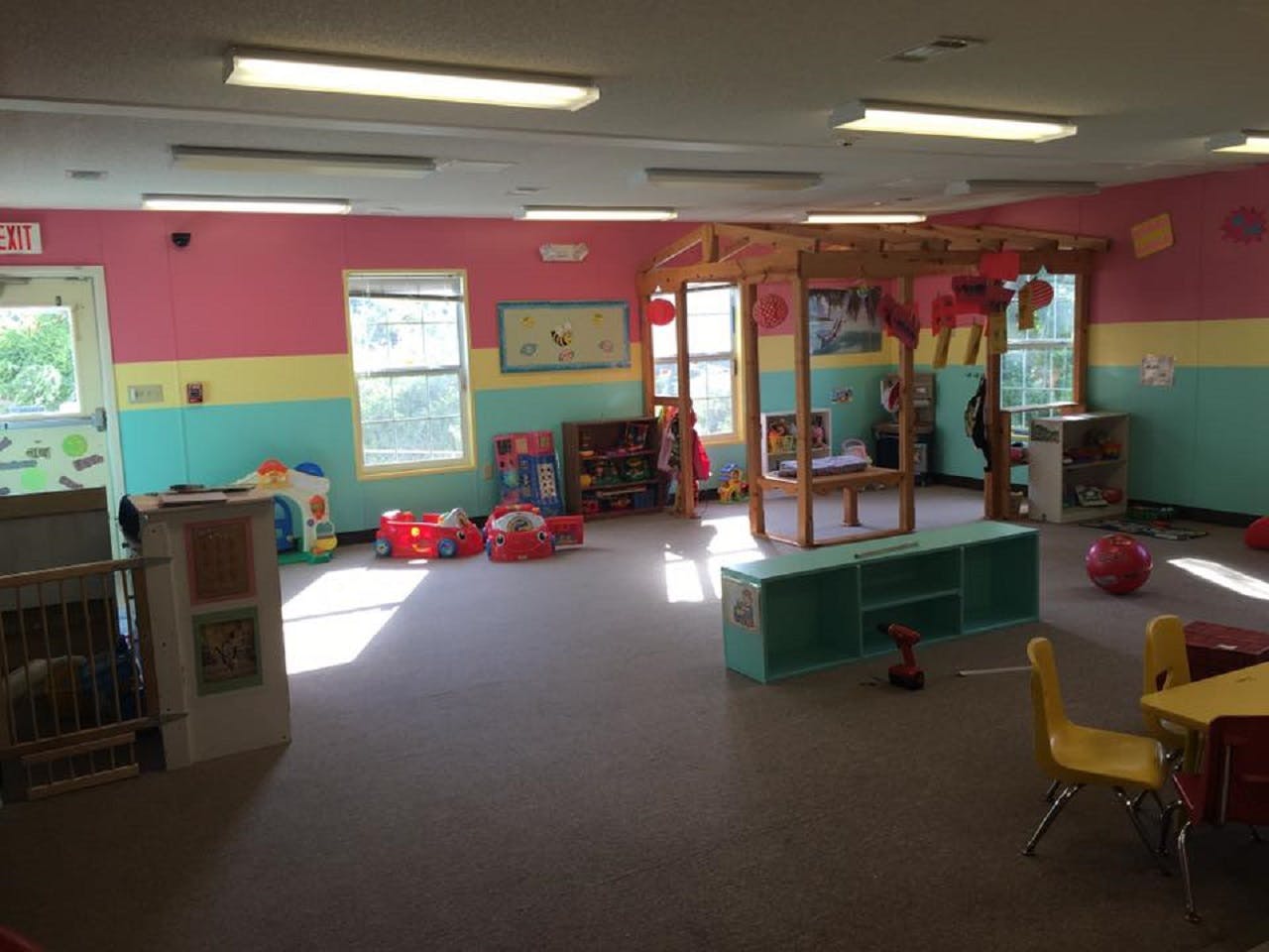 A colorful empty classroom with toys and furniture, sunlight streaming through windows