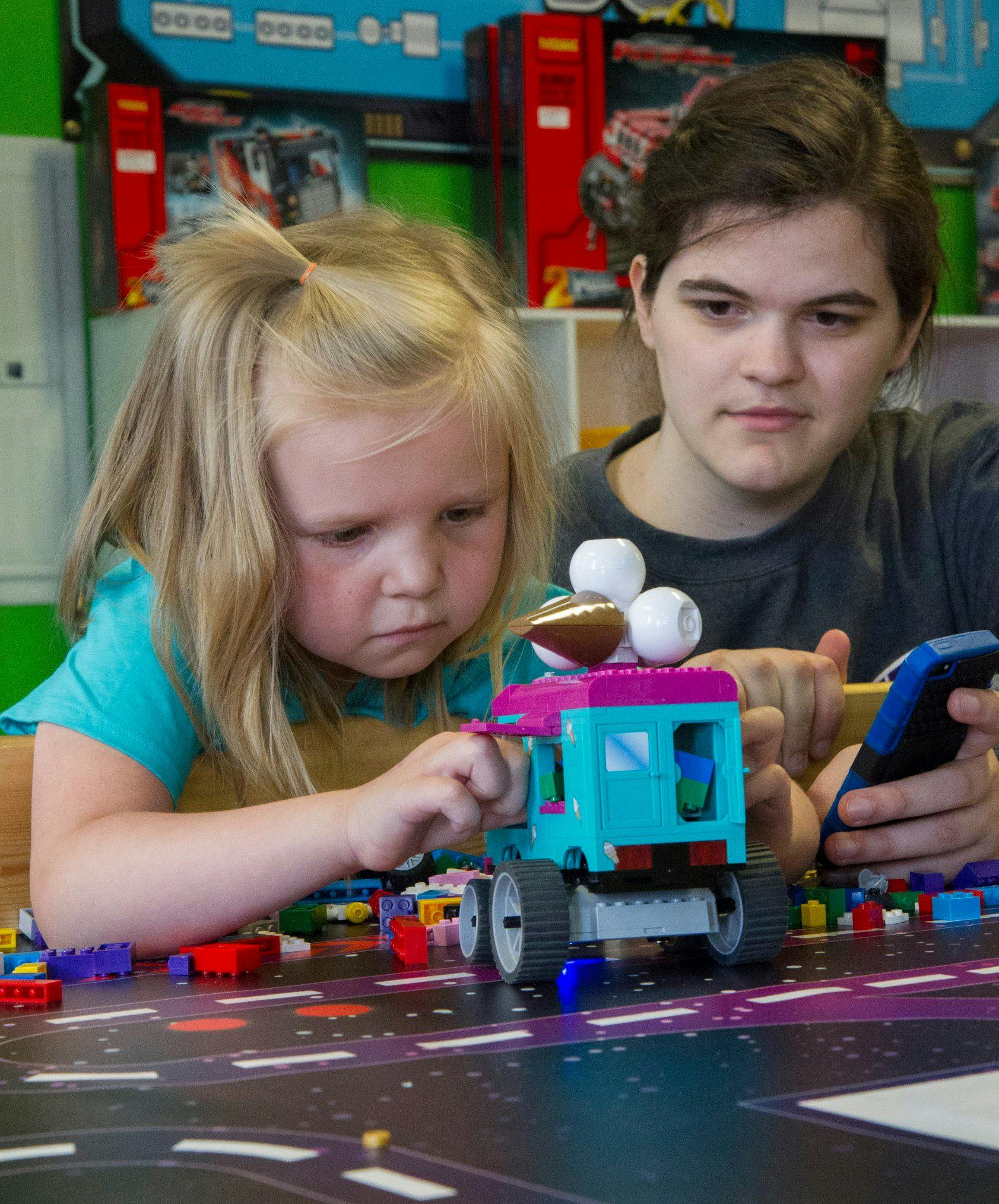Child and person building with toy blocks