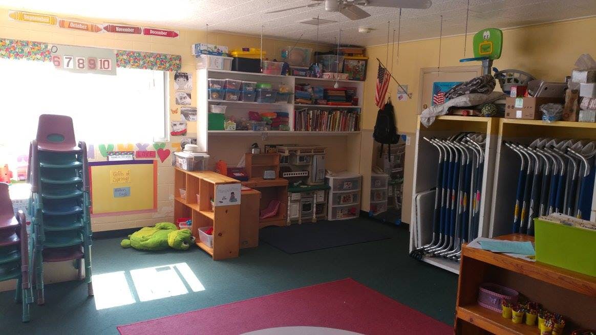 Classroom with stacked chairs, shelves, and a window
