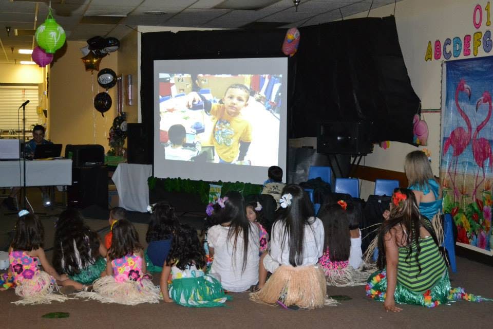 Children sitting on floor watching a projected image of a child