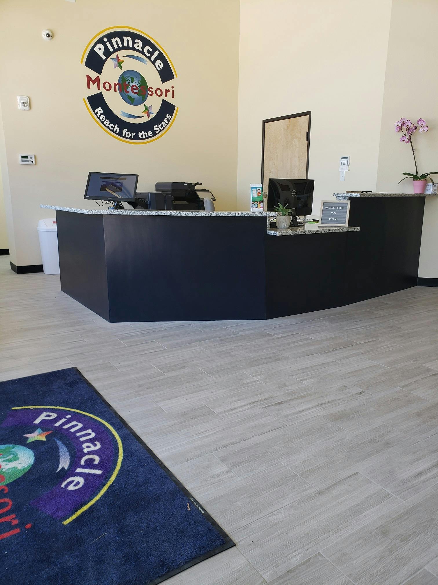 Reception desk with a logo on the wall that says Pinnacle Montessori