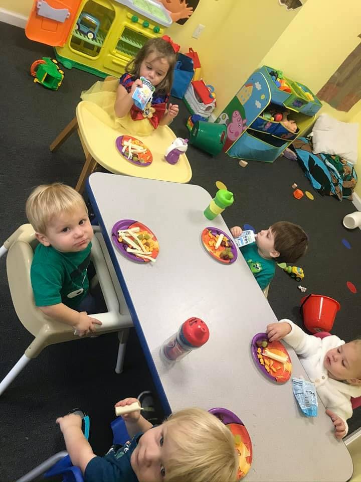 Children eating snacks at a table in a classroom