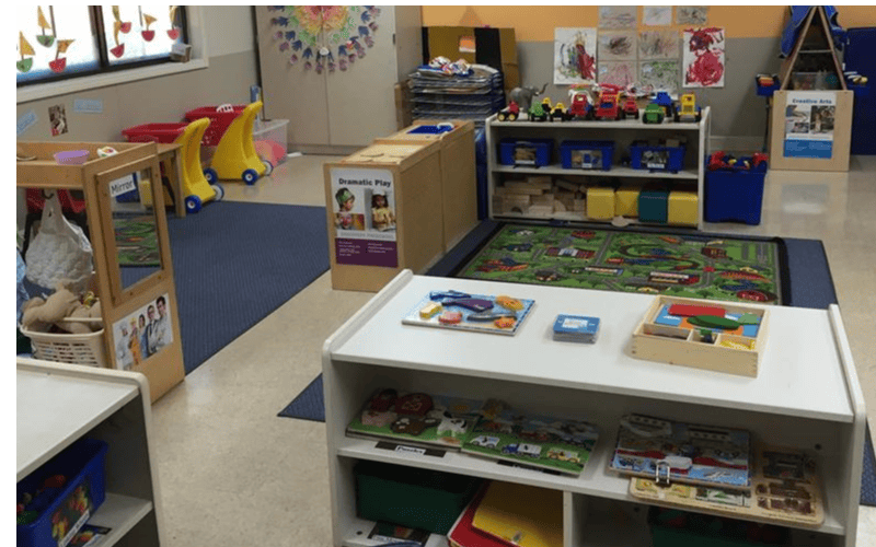 A classroom with toys, puzzles, and a play mat on the floor