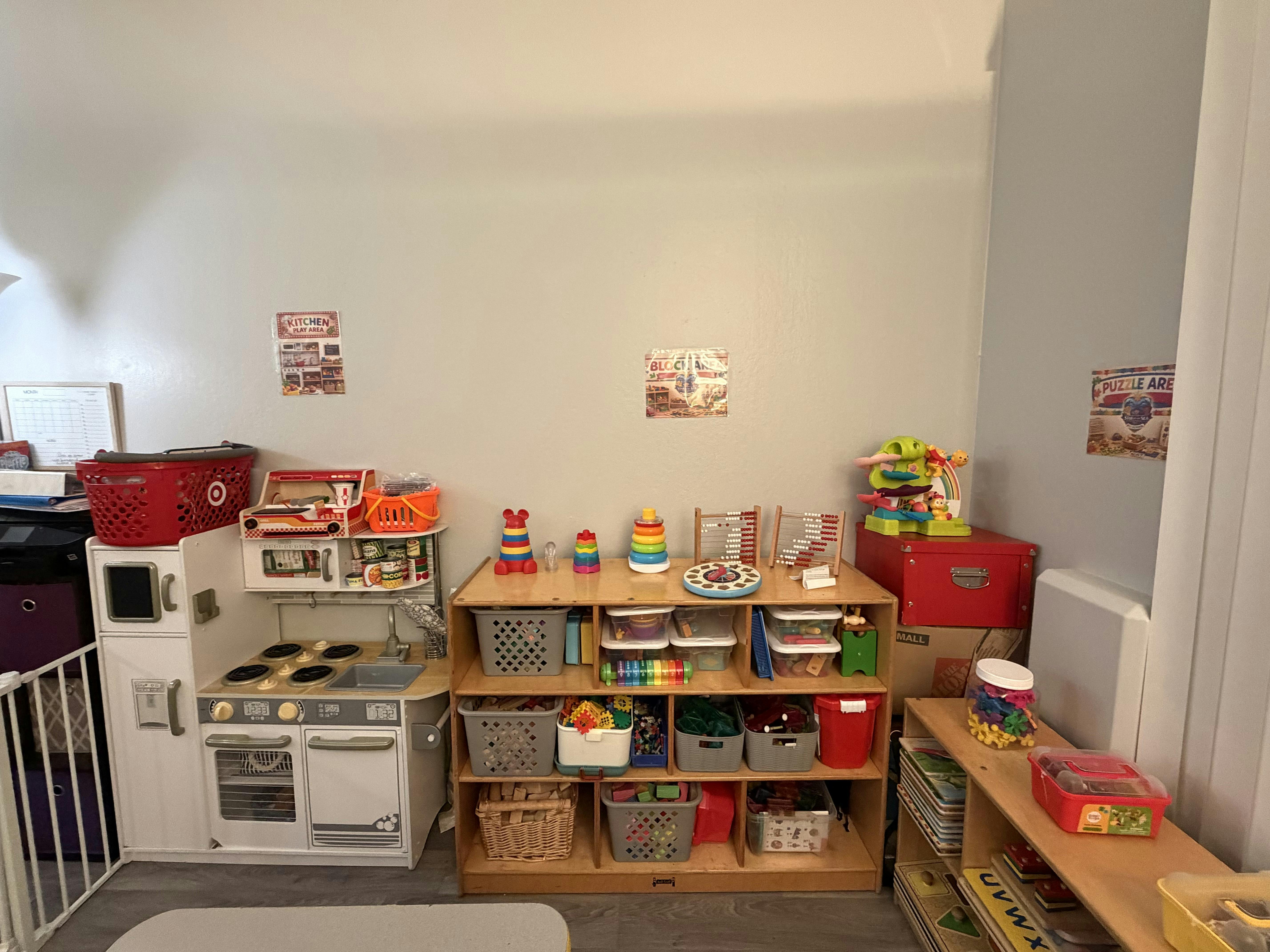 playroom with toy kitchen, shelving unit with various toys, and red storage boxes