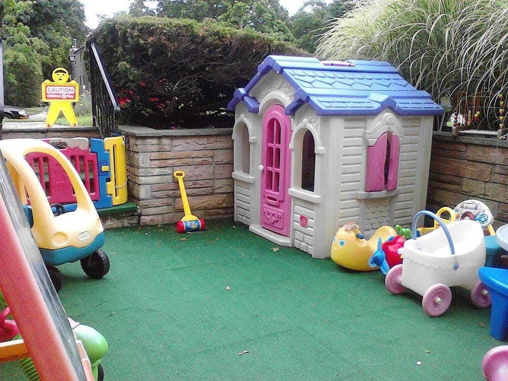 Outdoor play area with a toy house and various ride-on toys