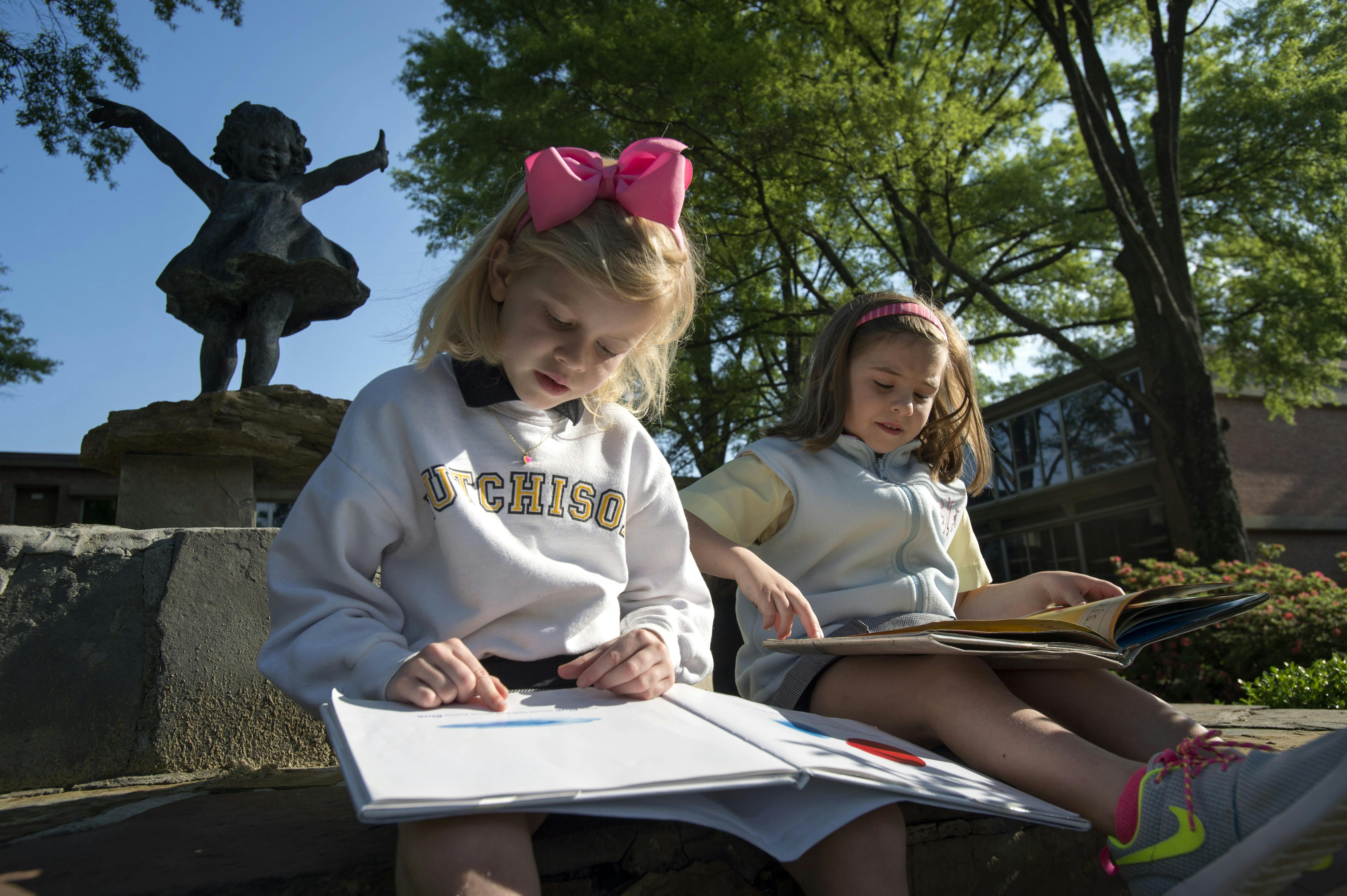 Two children reading books outdoors