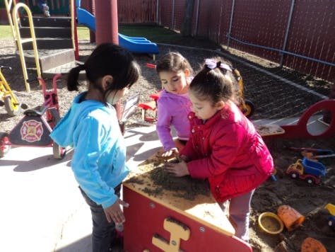 Three children playing in a sandbox