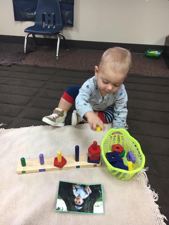 Child playing with colorful stacking toys and a basket of shapes