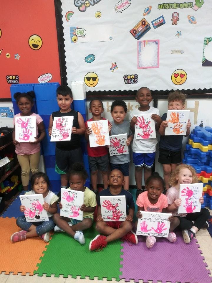 Group of children holding up artwork with handprints