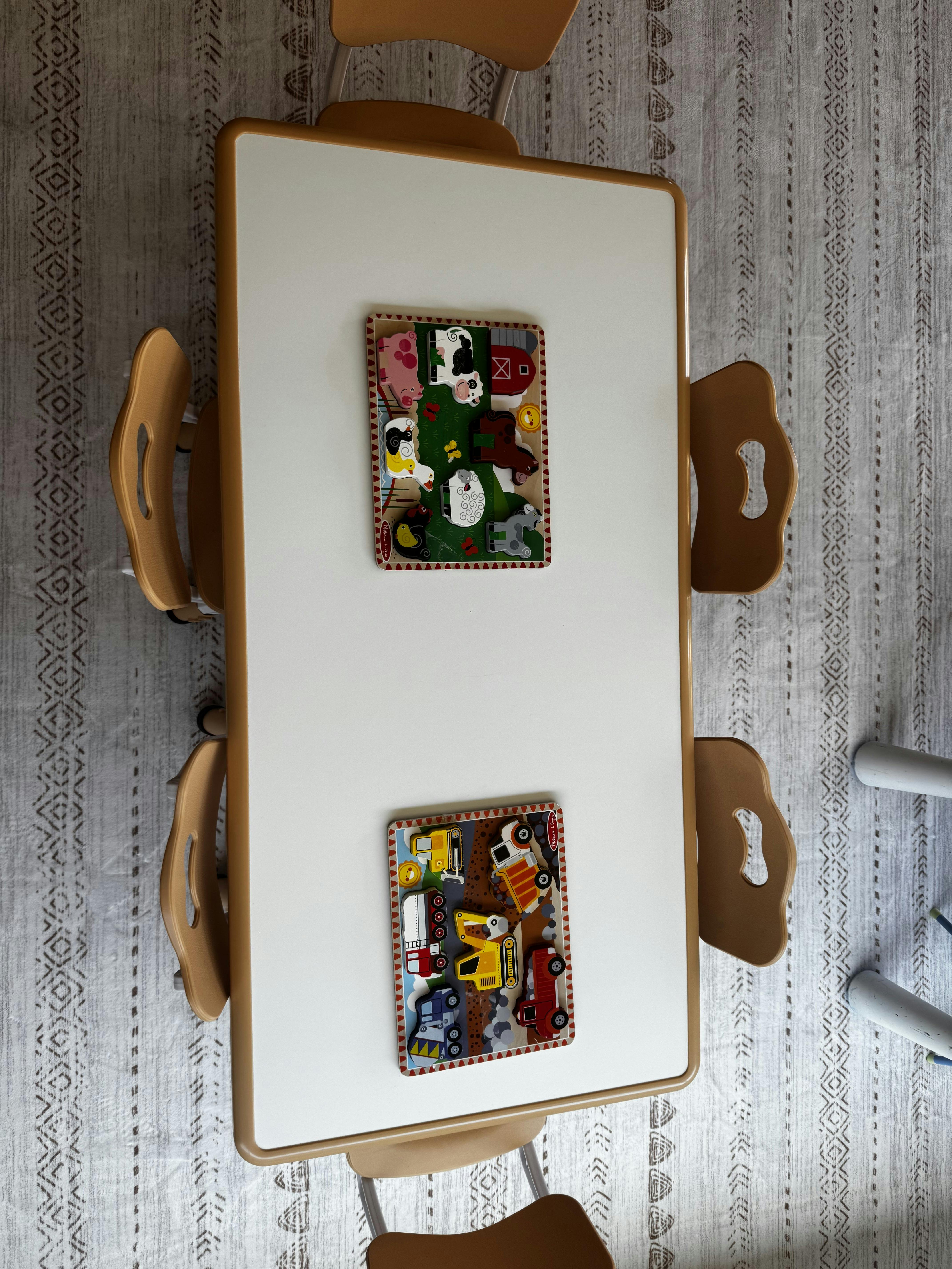 Wooden puzzles featuring farm animals and vehicles on a white play table