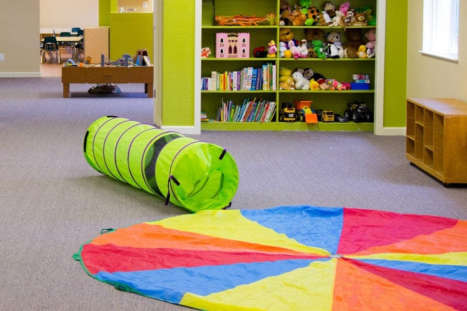 Play tunnel and colorful parachute on a carpeted floor in a playroom