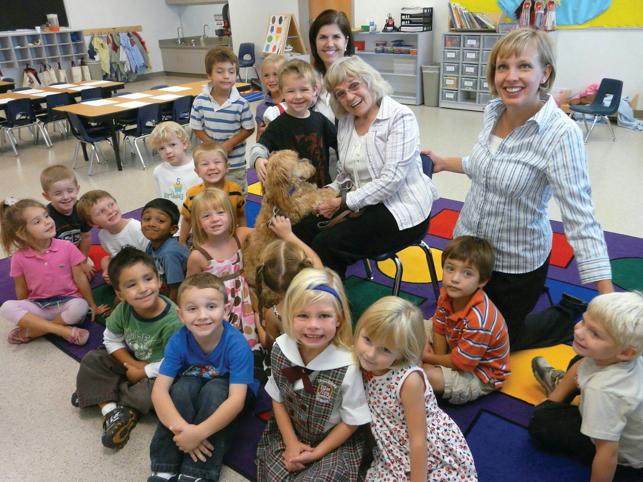 Adults and children with a dog in a classroom