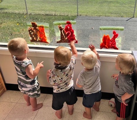 Four children playing with sensory bags on a window