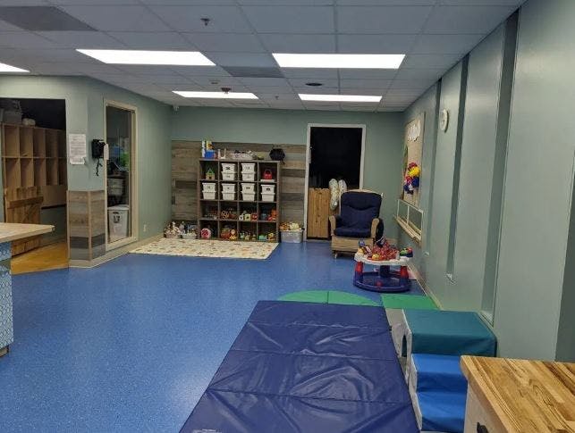 Playroom with blue floor, storage shelves, and soft play equipment