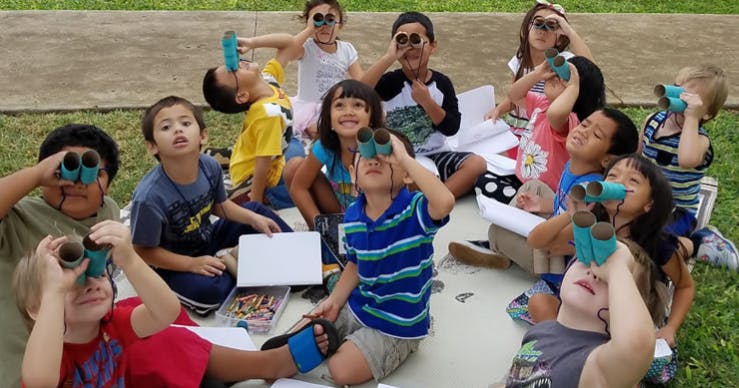 Group of children and teens looking through binoculars outdoors