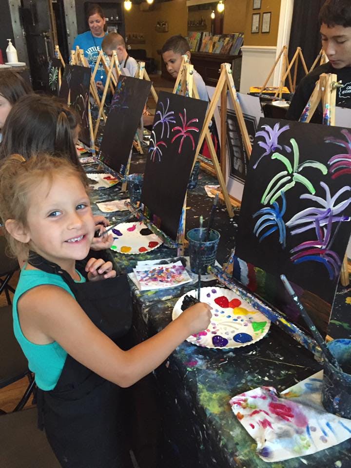 Child painting at an easel in a group art class