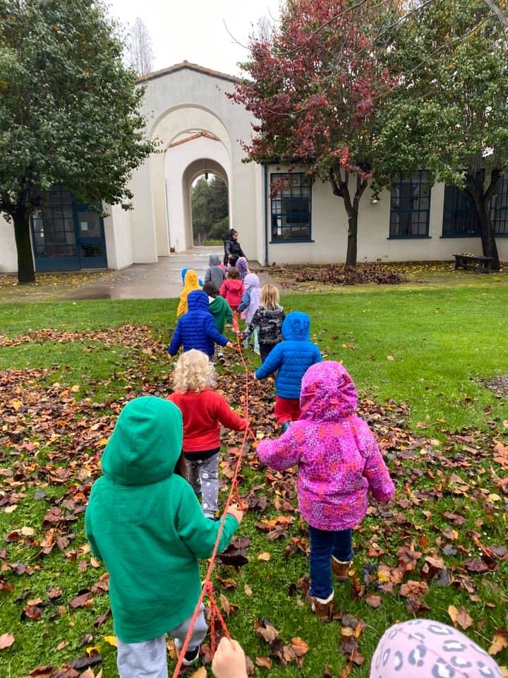 Children walking in a line holding onto a rope