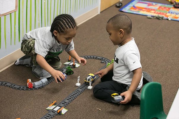 Two children playing with a toy train set on the floor