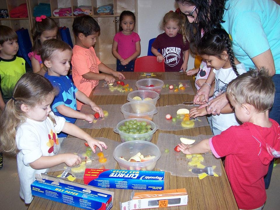 Adult and children preparing food at a table