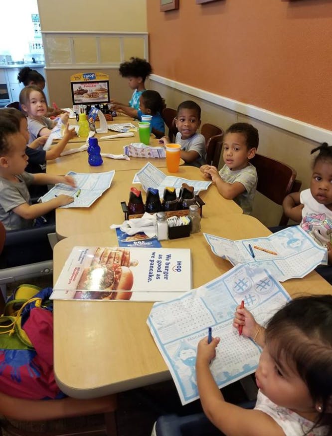 Children sitting at a long table with papers and drinks