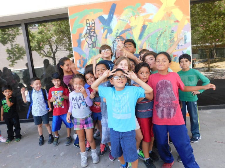 Group of children posing in front of a colorful mural