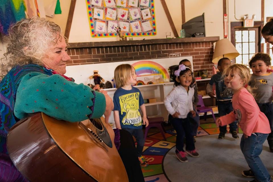 Person playing guitar for children in a classroom