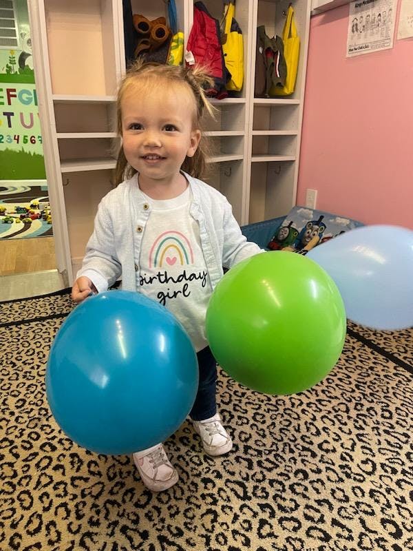 Child standing with two balloons