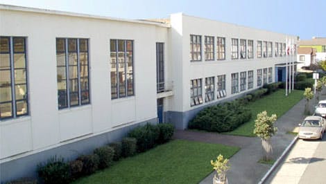 White building with multiple windows and a sidewalk with parked cars