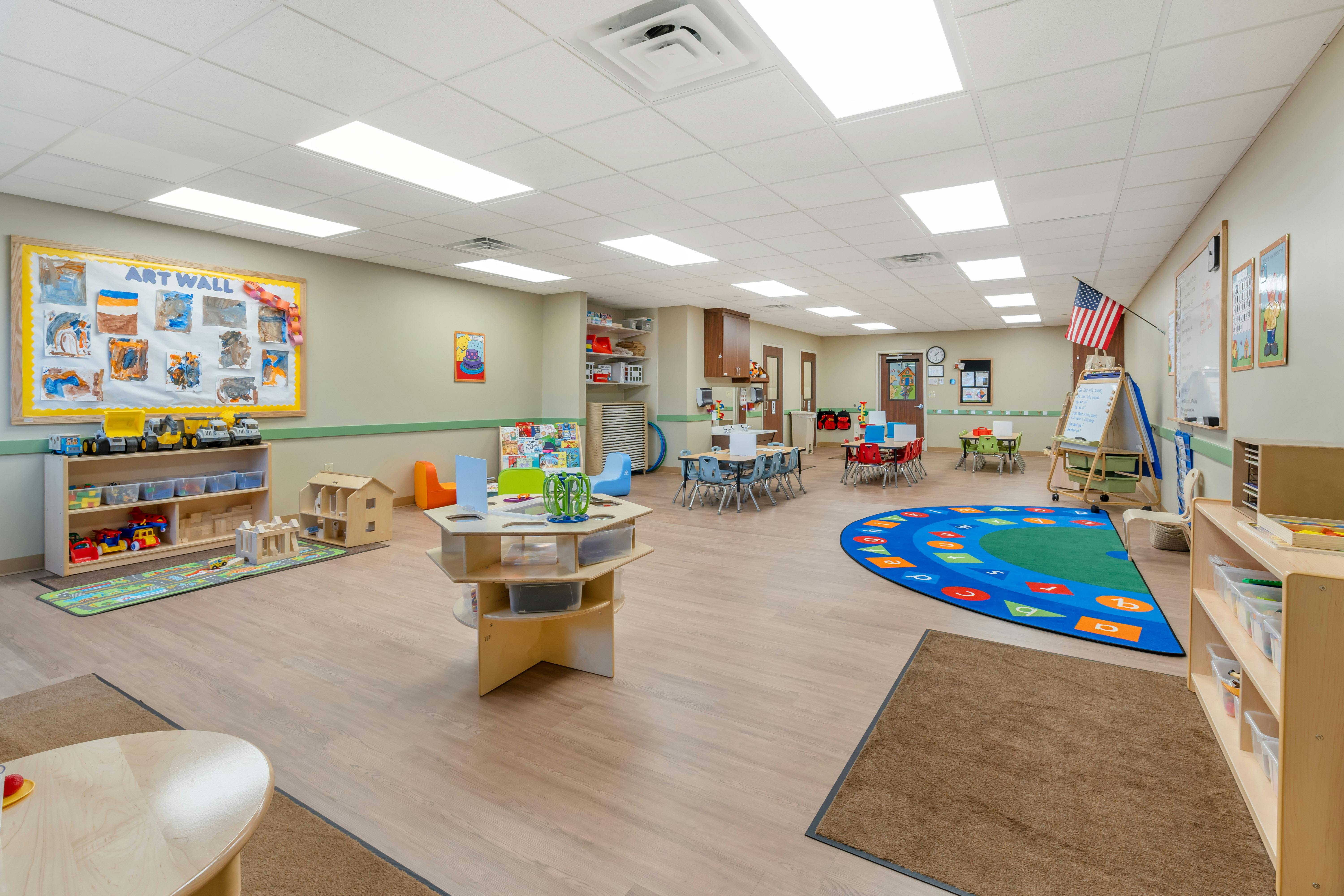 Classroom with tables, chairs, toys, and an "ART WALL" display