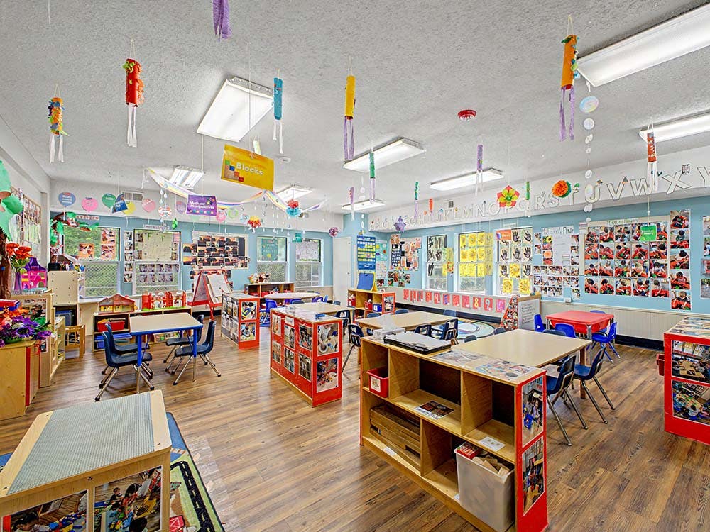 A colorful classroom with small tables and chairs, and decorations