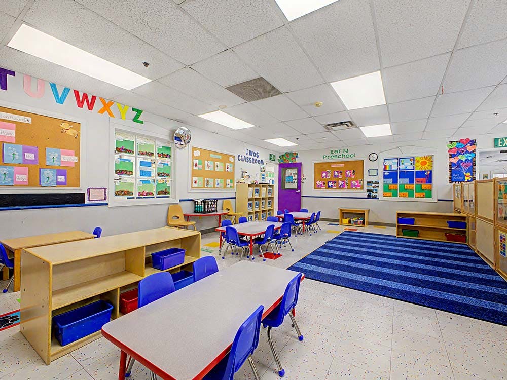 Empty classroom with small tables and chairs, colorful decorations on walls