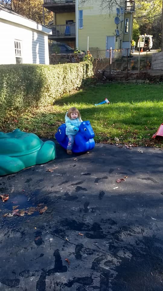 Child on a blue plastic rocking horse toy outdoors