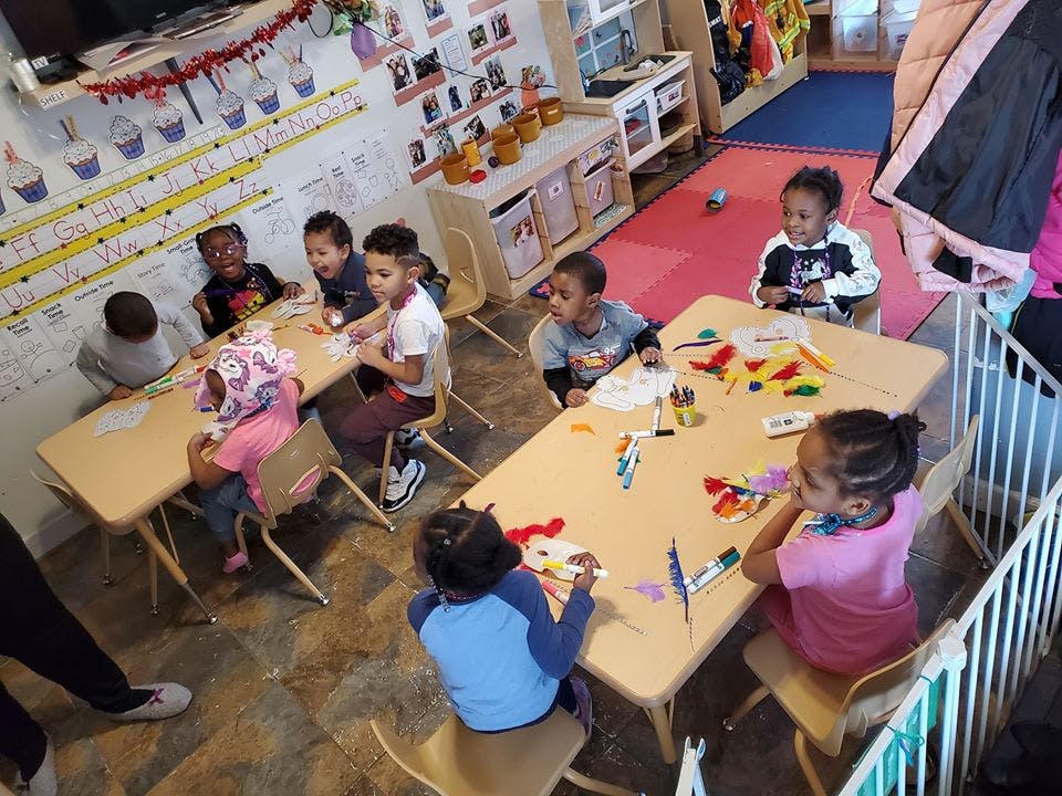 Children sitting at tables in a classroom, engaged in activities