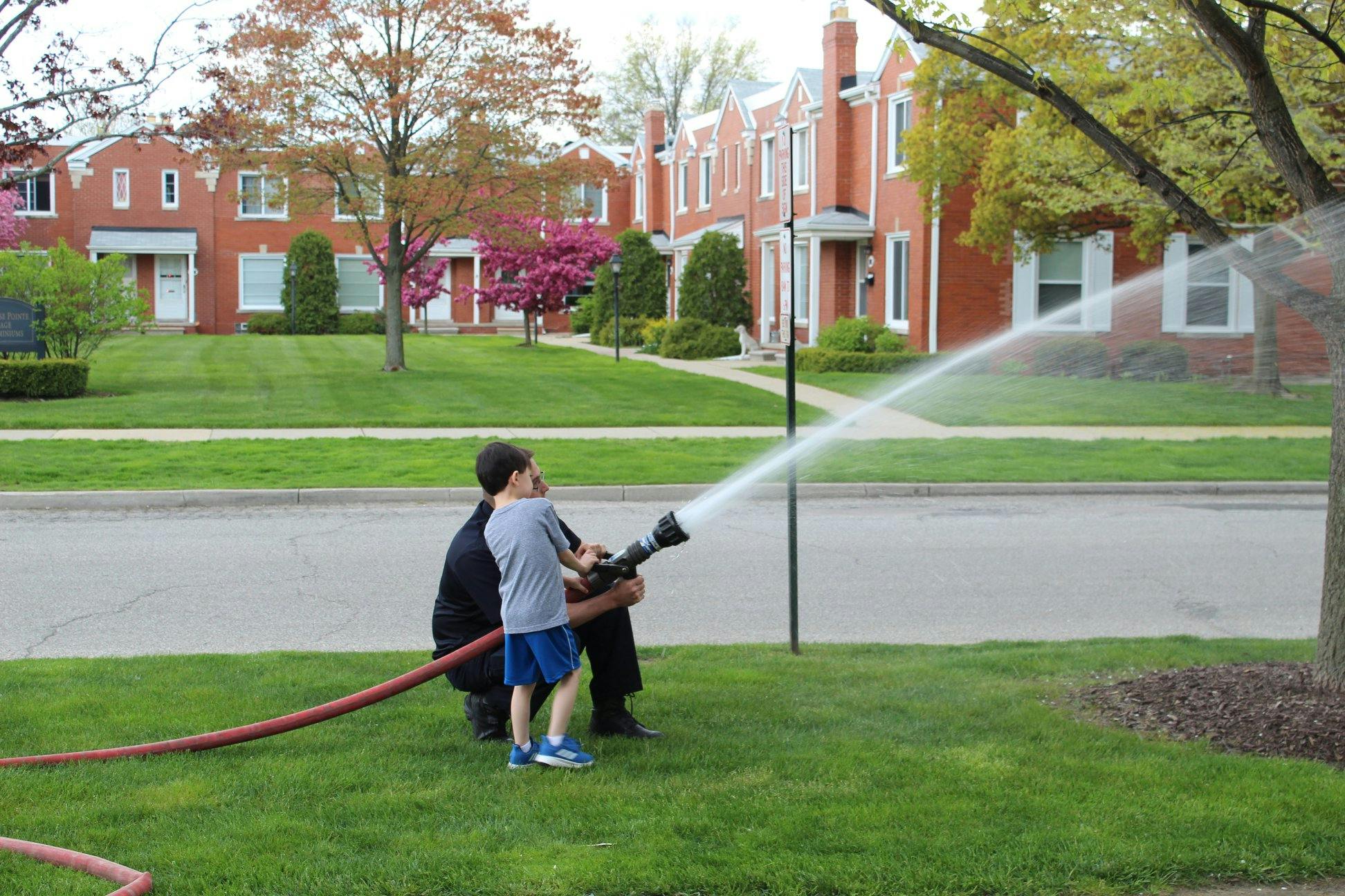 Person and child holding a fire hose spraying water