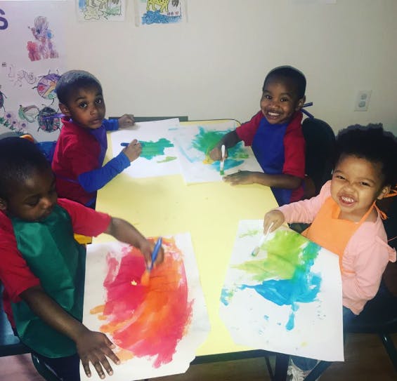 Four children painting at a table