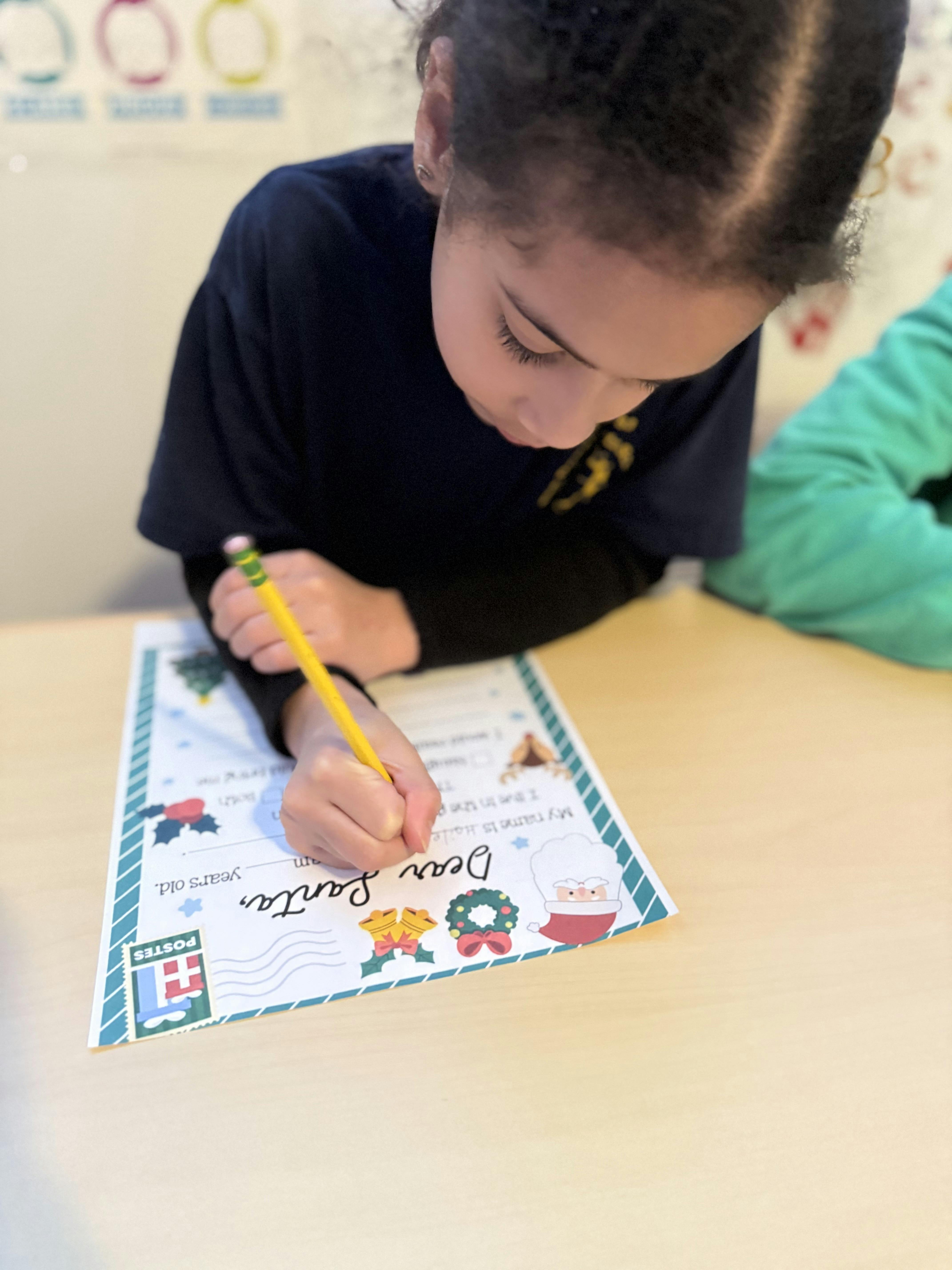 Child writing a letter to Santa with a pencil
