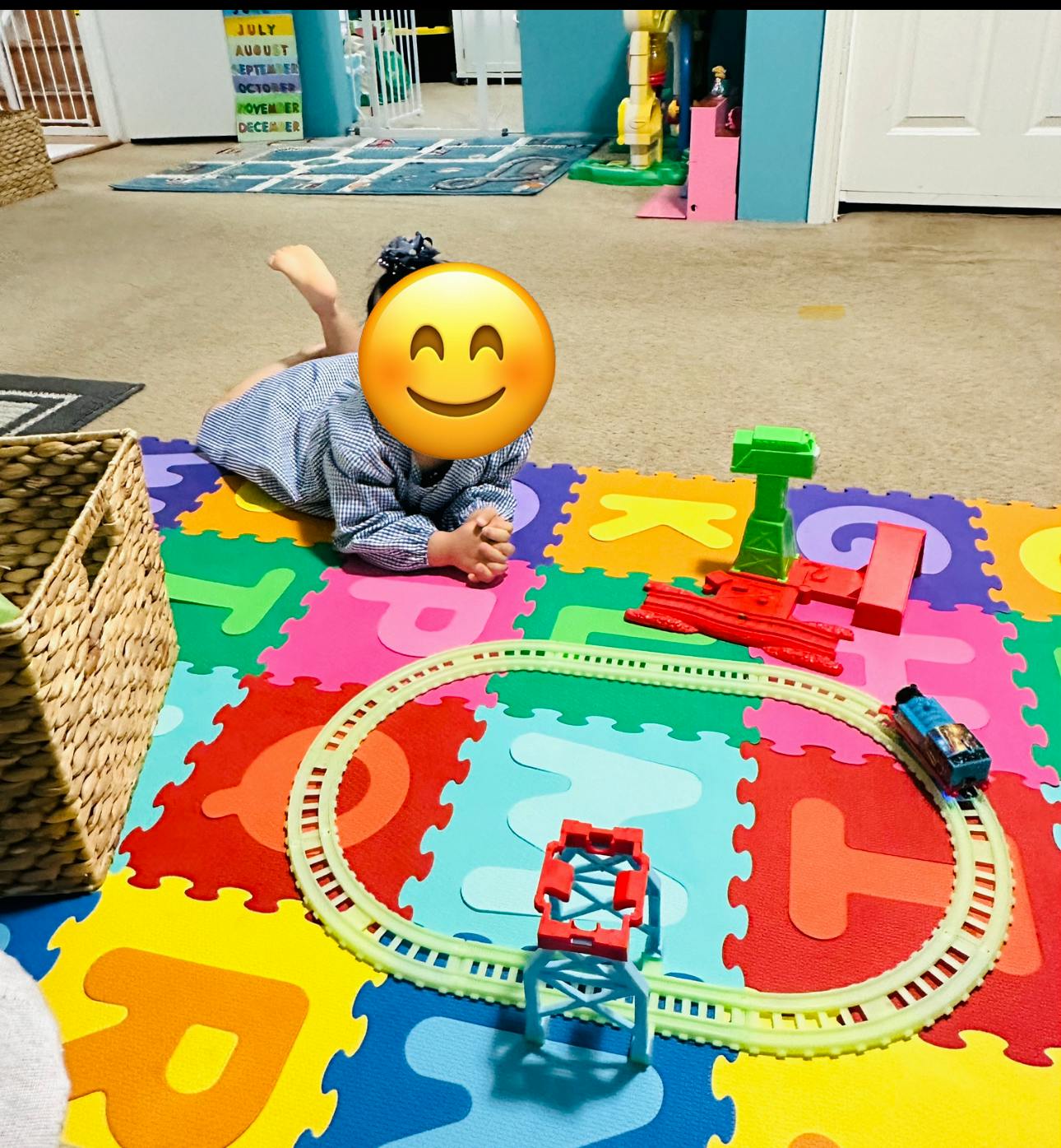 Child playing with a toy train set on a colorful alphabet mat