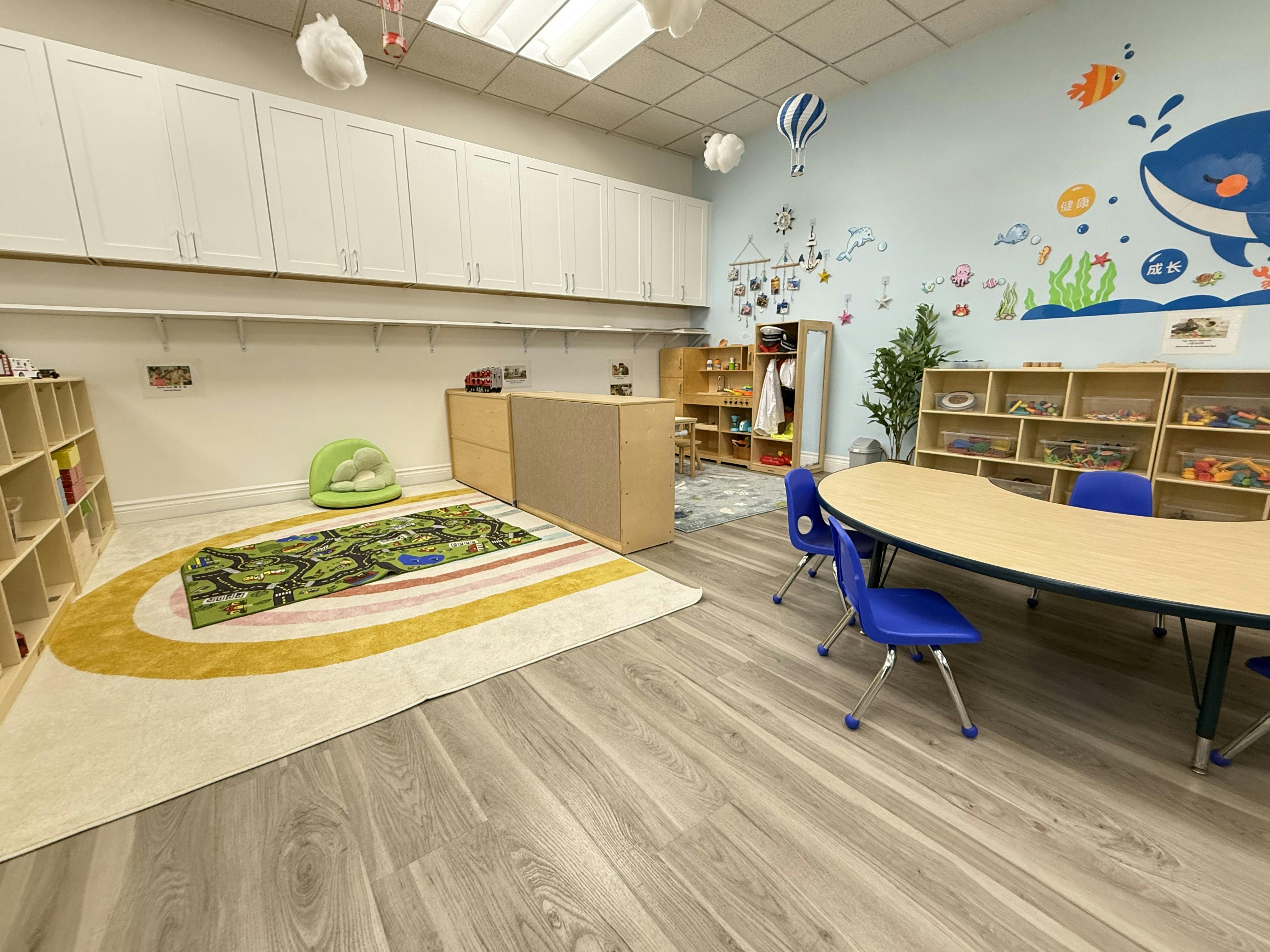 Classroom with a whale mural, tables, chairs, and a rainbow rug