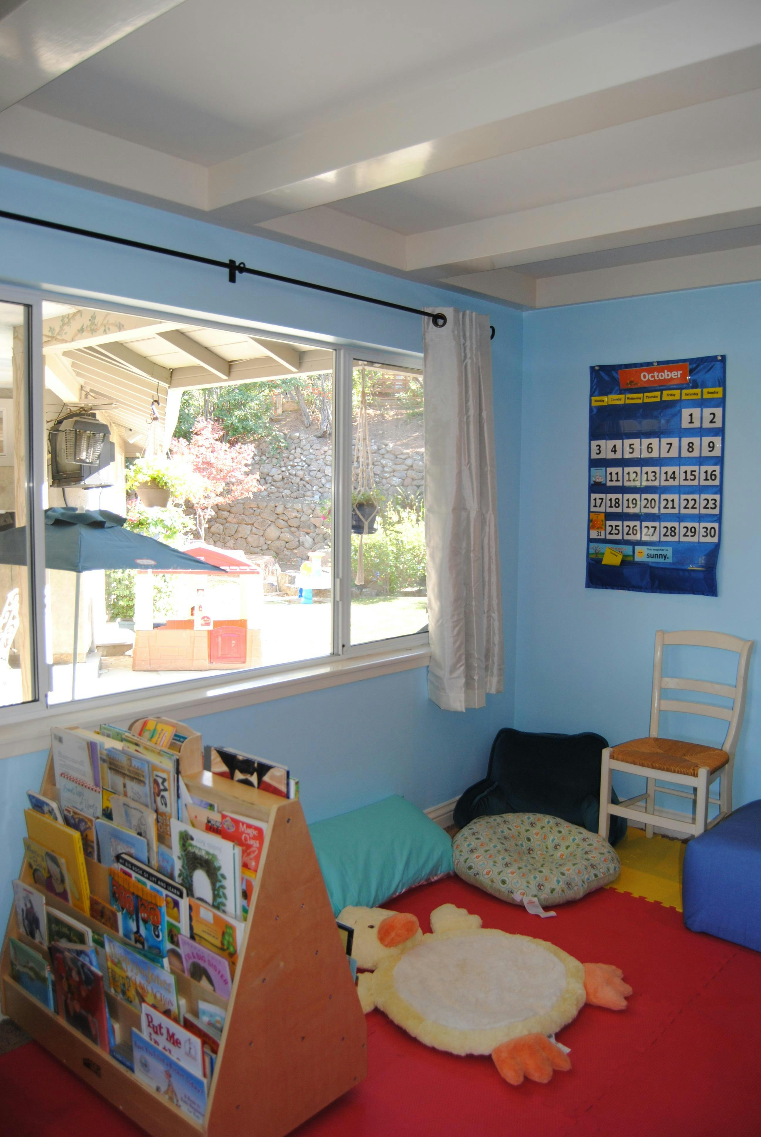 Children's playroom with a book display, floor cushions, and a calendar