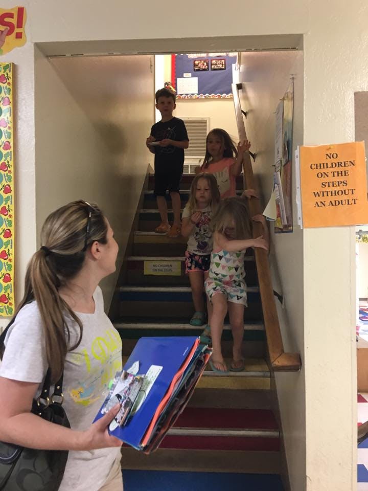 Person holding a folder looking at children on a staircase
