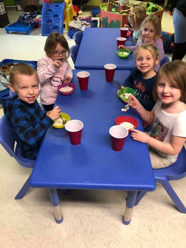 Children sitting at a blue table with bowls and cups