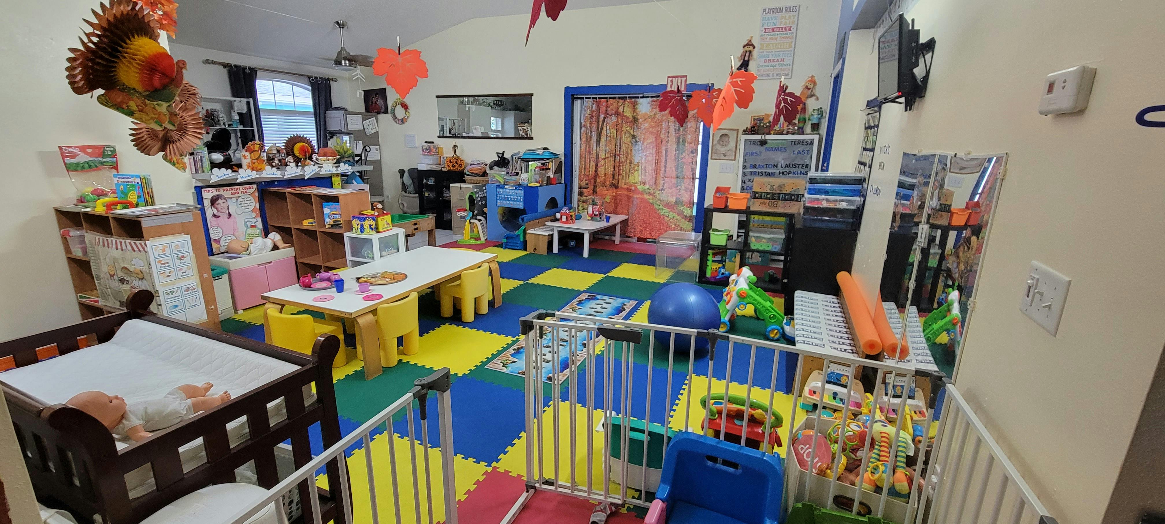 Playroom with a crib, small tables and chairs, and play mats