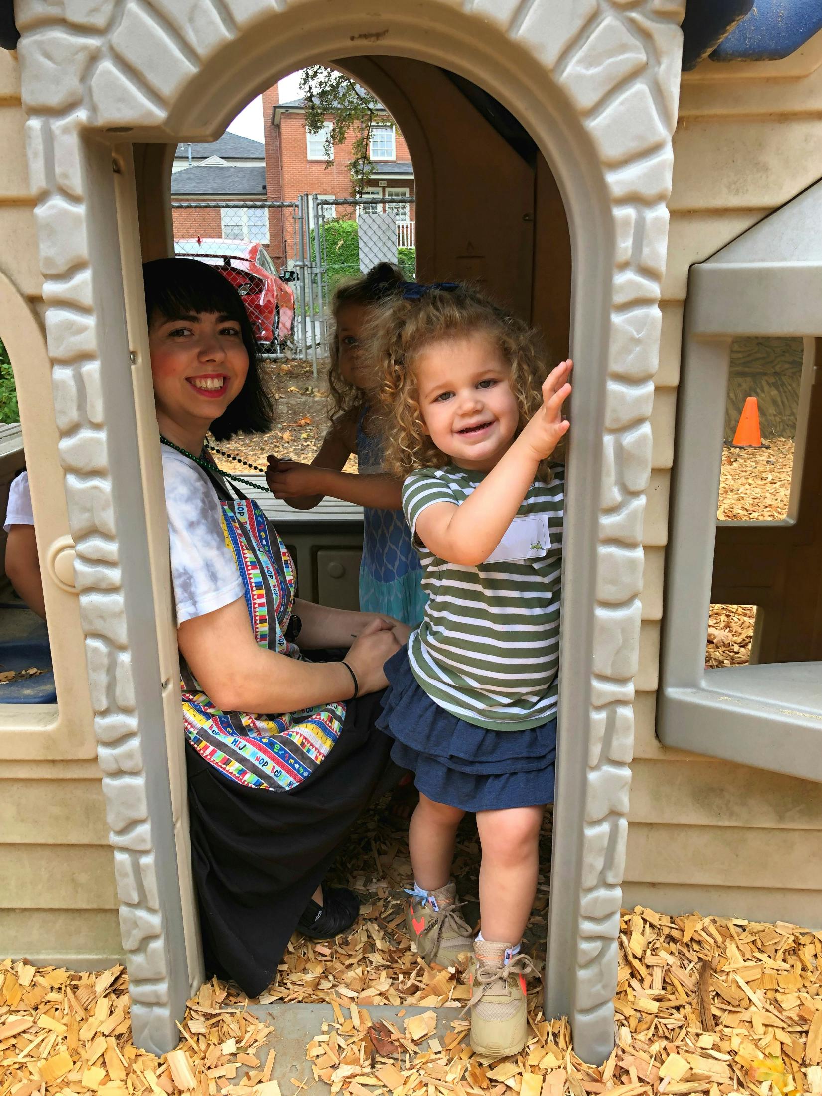Person and two children in a playhouse