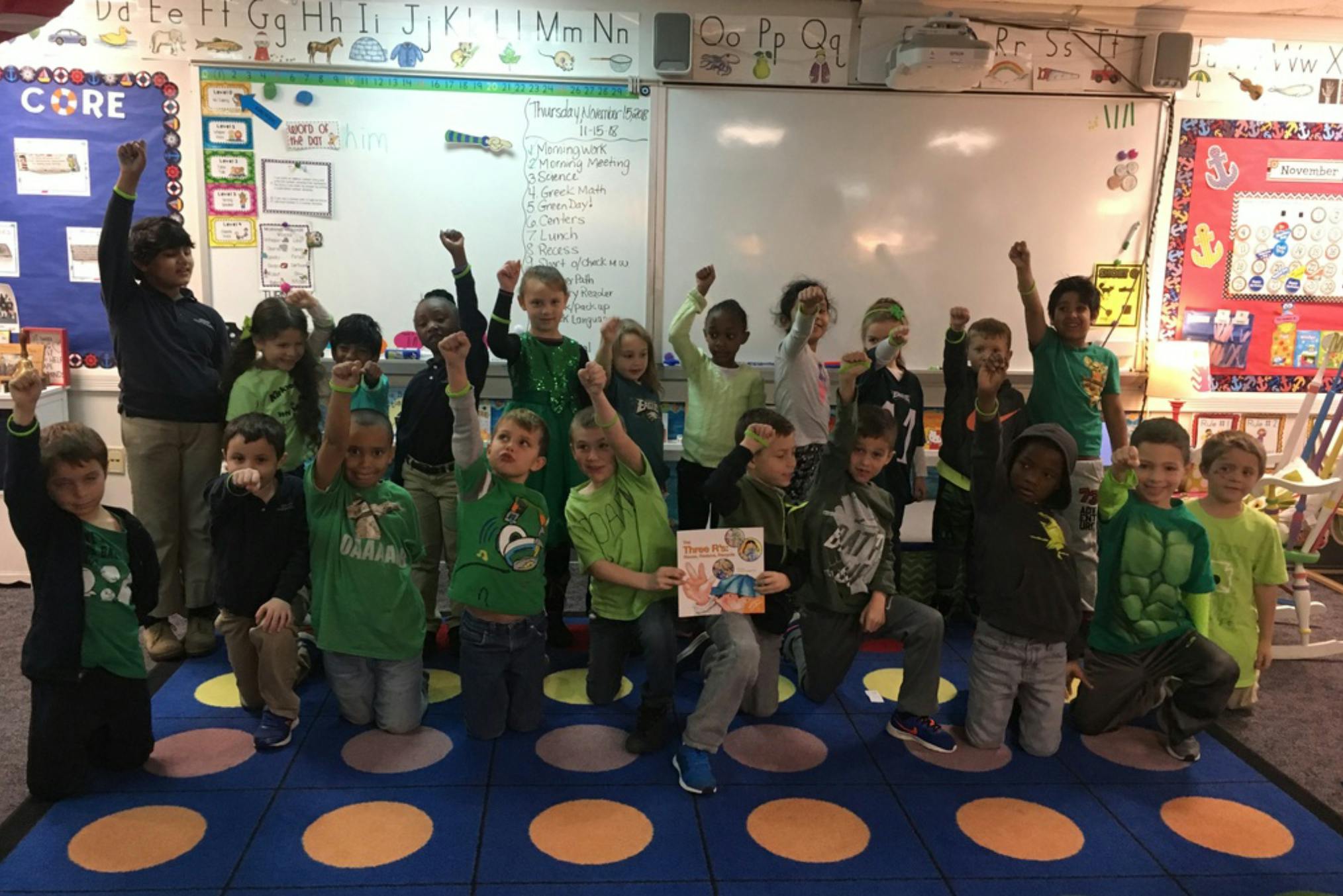 Group of children and an adult raising their fists in a classroom