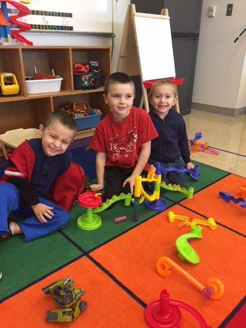Three children playing with toys on a colorful rug