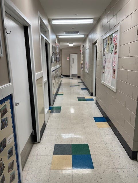 Long school hallway with tiled floor and display boards on brick walls