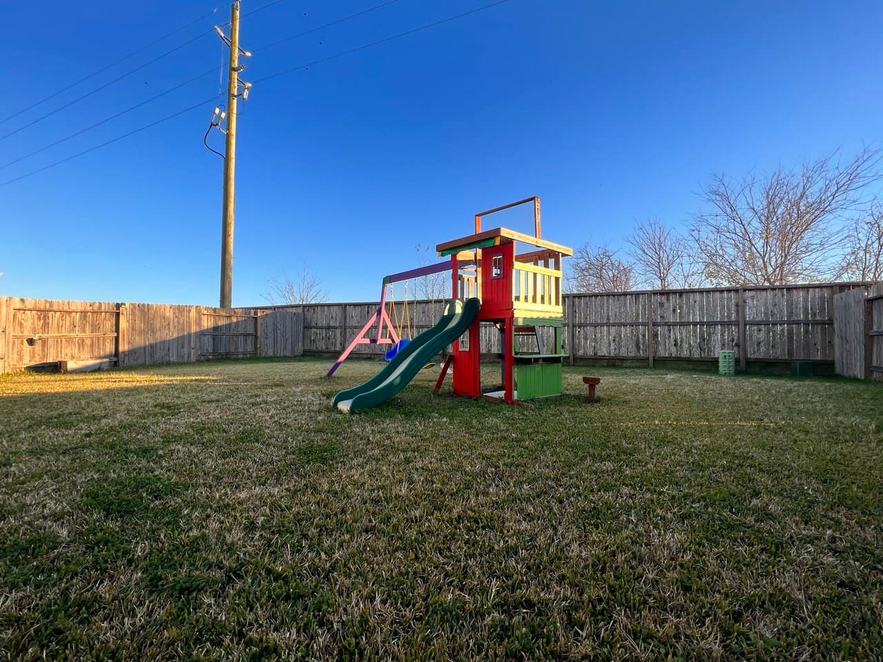 Backyard with a wooden fence and a colorful playset