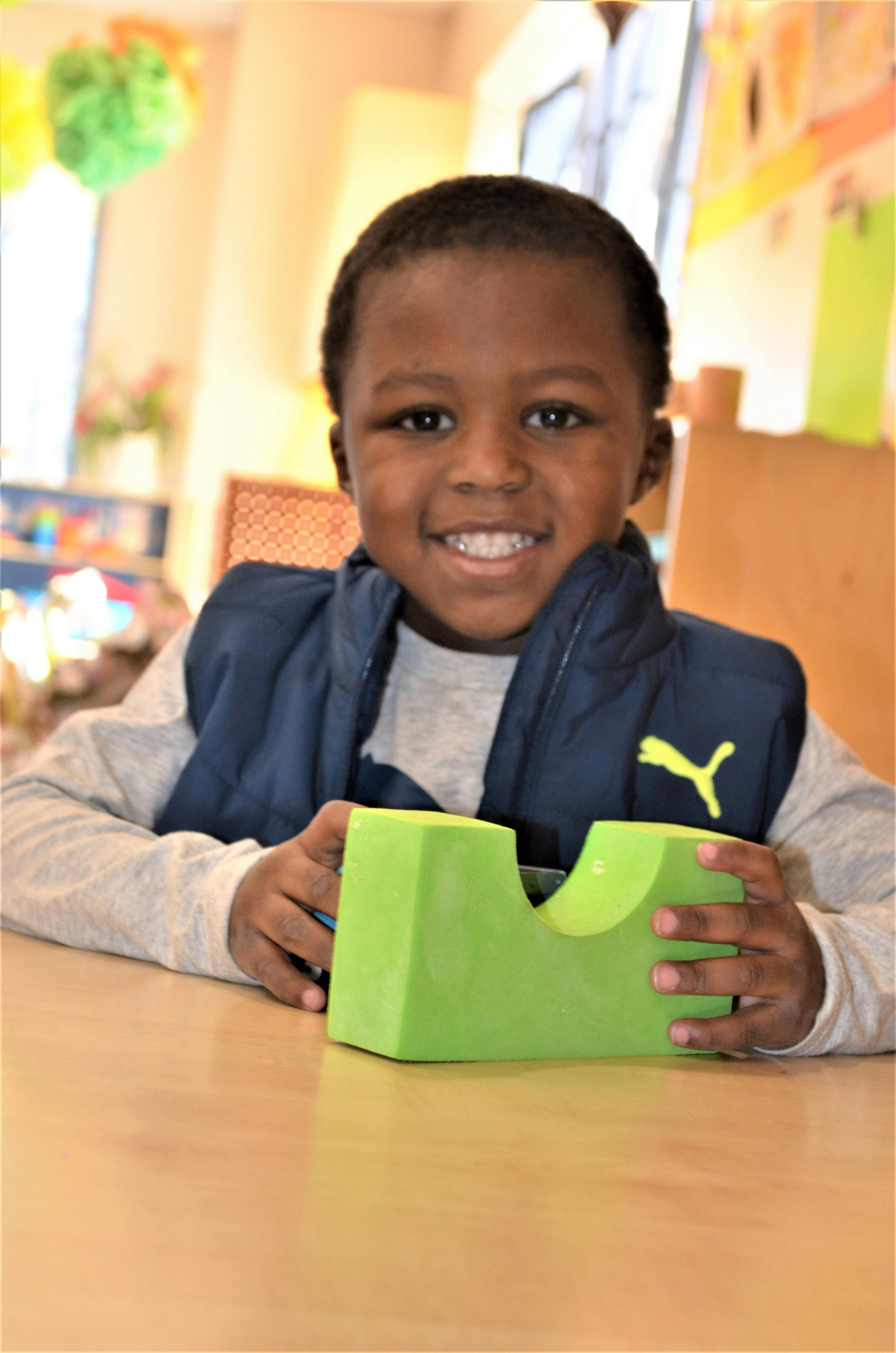 Child holding a green object on a table