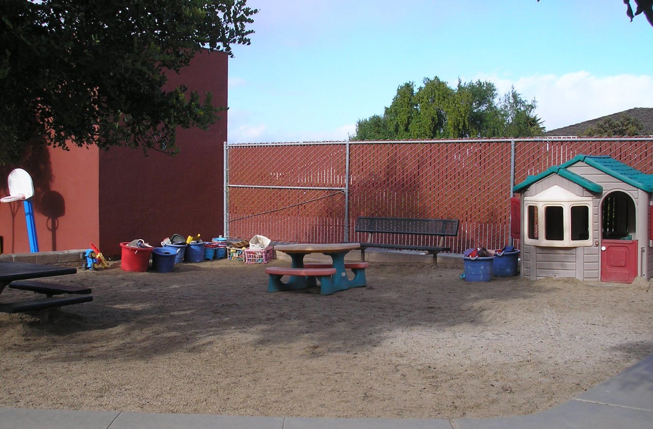 Outdoor play area with a small playhouse, picnic tables, and toys